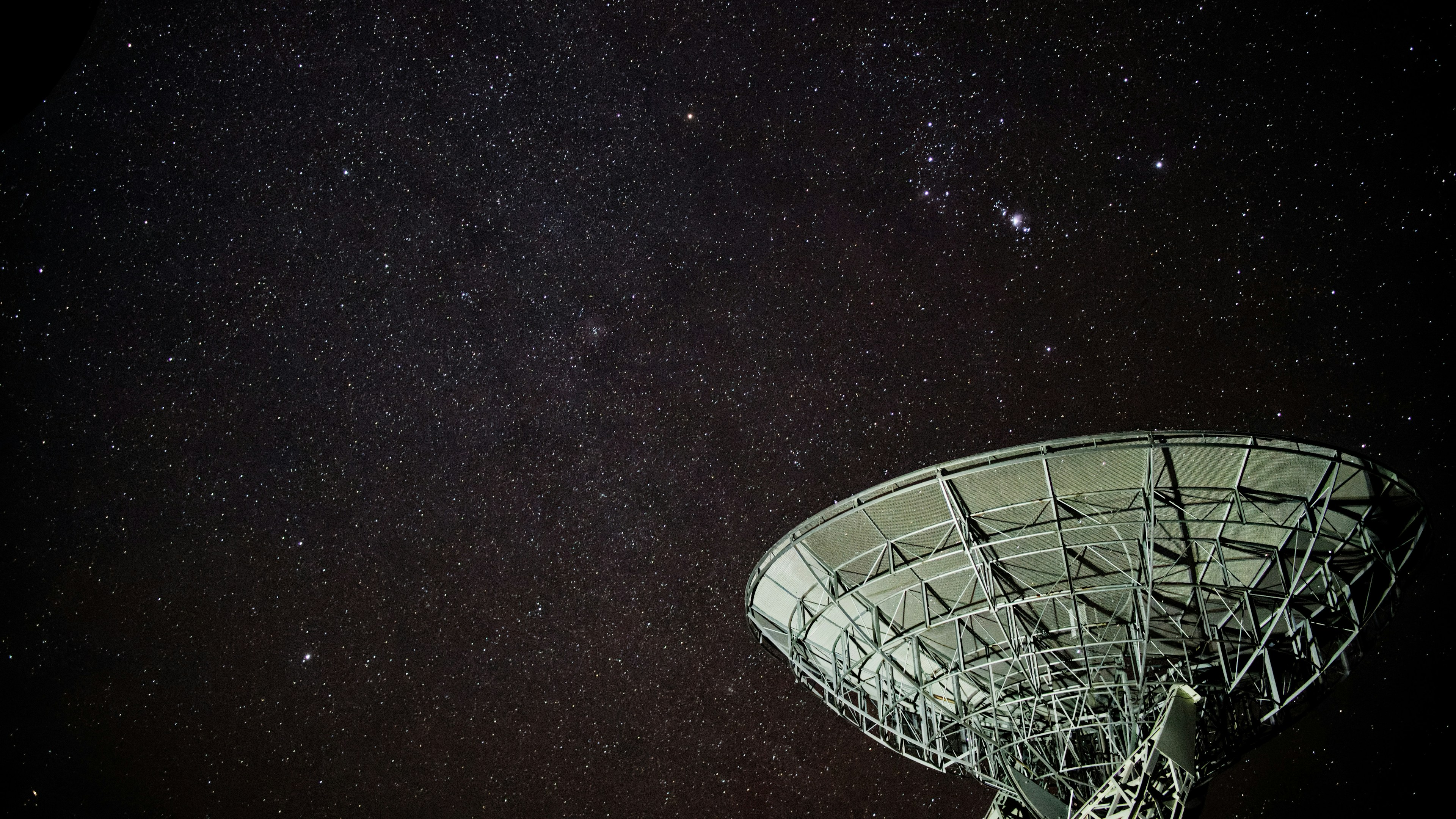 A radio telescope dish pointed at a starry night sky